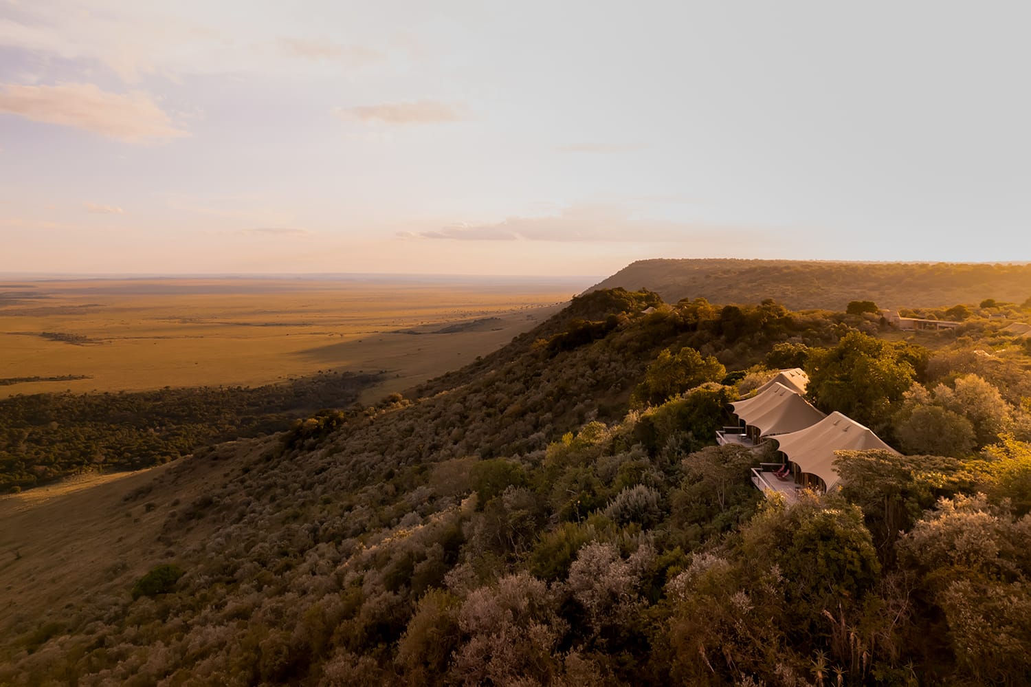Scenic view of a landscape with a building on a hill at sunset.