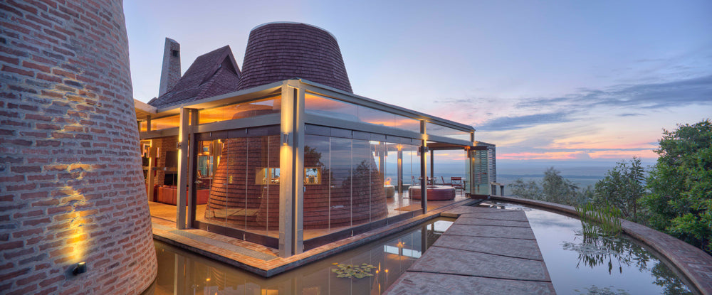 
“A modern, glass‑roofed sanctuary suspended above the Maasai Mara, where architecture dissolves into landscape. The house captures the drama of sunset through transparent planes, an infinity pool that mirrors the horizon, and minimalist forms that celebrate openness, serenity, and the raw beauty of Angama Mara.”