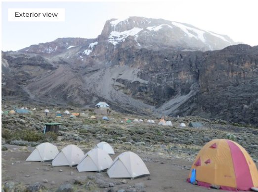 Tents set up in a mountainous area snow-capped peaks of mount Kilimanjaro.