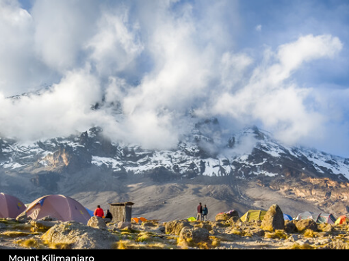 Scenic view of Mount Kilimanjaro with tents and people at a base camp.
