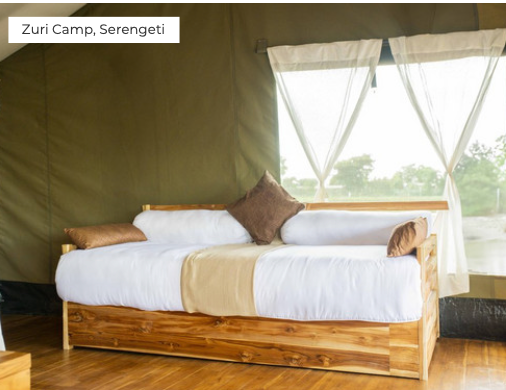 Bed inside a tent at Zuri Camp, Serengeti with a view of the outside.